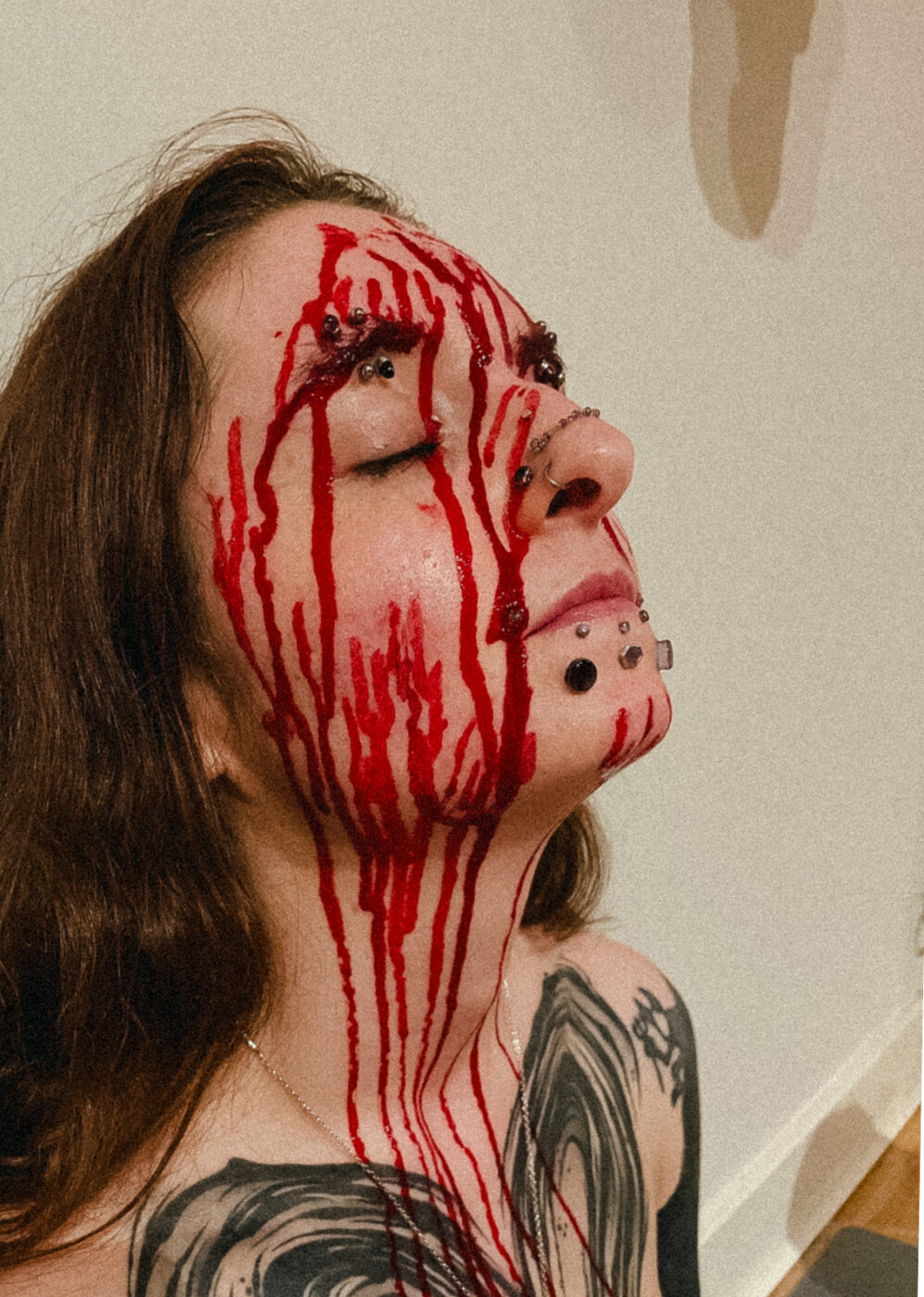 A woman with blood trailing down her face from recently-removed needles.
